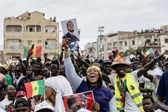 Une partisane du Premier ministre sénégalais Ousmane Sonko danse en tenant un portrait de lui lors d'un rassemblement à Dakar
