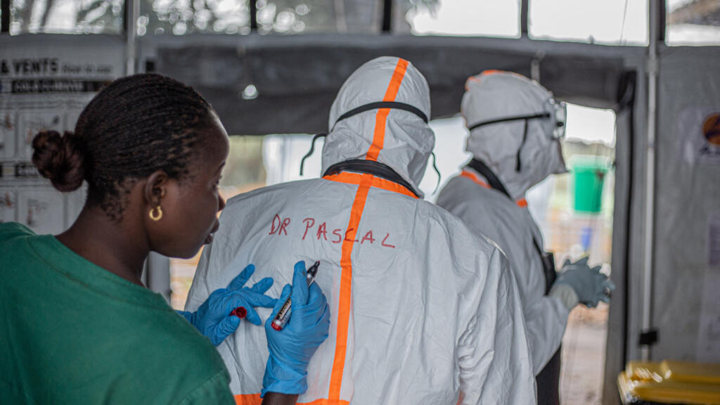 Agent d'hygiène notant le nom d'un médecin sur sa combinaison de protection dans un centre de traitement Ebola à Bunia, en Ituri (RDC), le 13 juillet 2026.